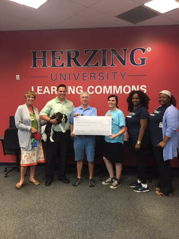 Mark Zanin accepts a check from Herzing University employees.